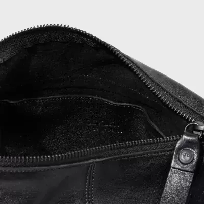 Bolsa preta em pele com fecho de correr aberto, mostrando interior forrado em preto