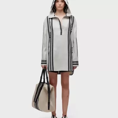 Mulher com túnica de algodão branca com riscas pretas e mala de tecido bege