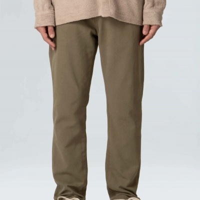 Pessoa com calças castanhas, sapatos creme e casaco bege