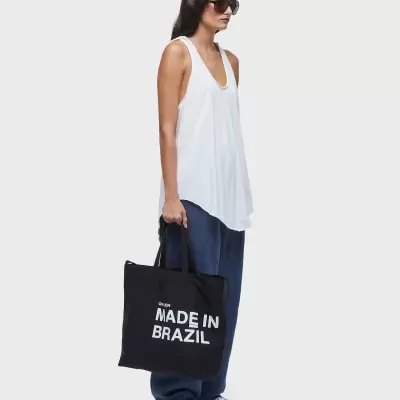 Mulher com mala preta com texto Made in Brazil