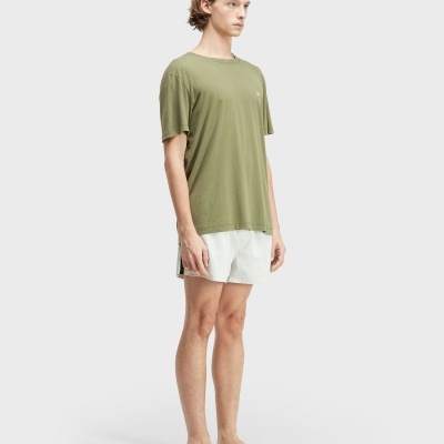 Homem com t-shirt verde-oliva e calções brancos com faixa preta