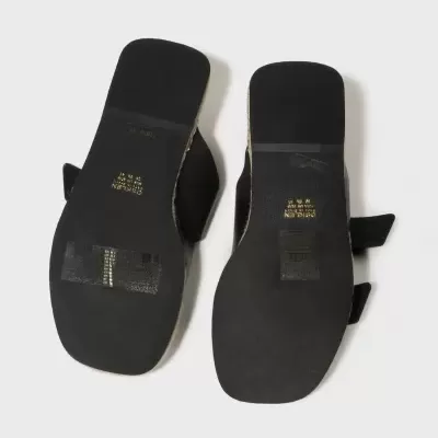 Vista das solas de sandálias pretas de sola plana com texto dourado