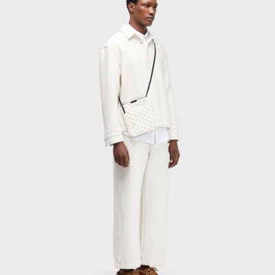Homem vestido de branco com sapatos castanhos e mala branca com padrão de escama