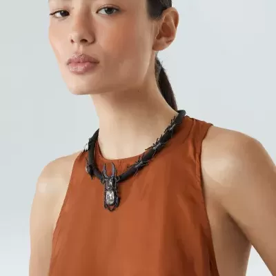 Colar preto com pendente de inseto e vestido castanho liso