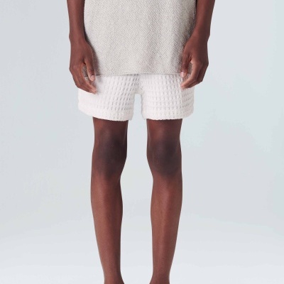 Calções brancos texturizados e sandálias pretas em modelo com fundo claro