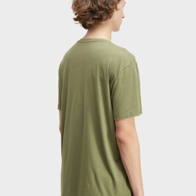 Pessoa de costas com t-shirt verde e calções brancos com riscas pretas