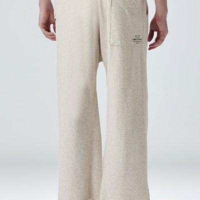 Calças largas bege de tecido com bolso traseiro e etiqueta, vista de costas