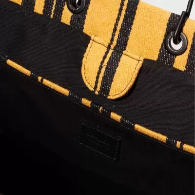 Interior da bolsa com padrão às riscas amarelas e pretas e etiqueta preta