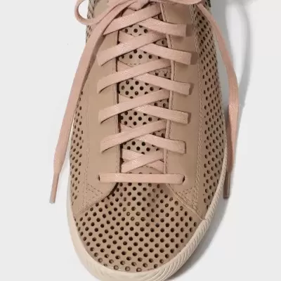 Tênis bege perfurado com atacadores e sola clara visto de cima