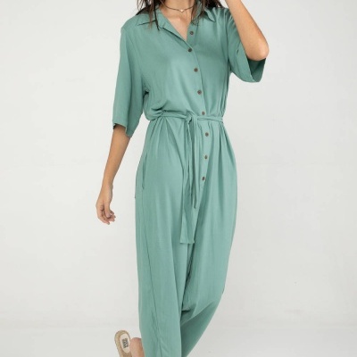 Macacão verde-água feminino com botões e cinto, usado com sandálias rasteiras.