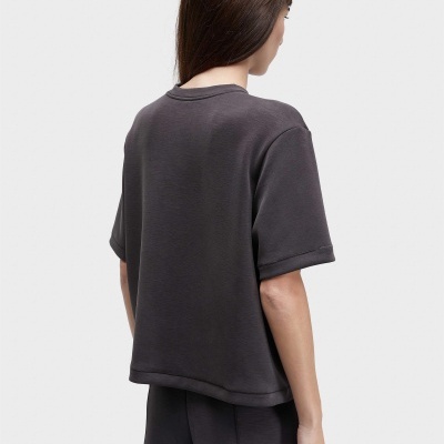 Pessoa de costas com t-shirt cinza escuro e calças combinando em fundo branco.