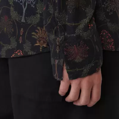 Camisa escura com padrão de árvores e folhas e calças pretas