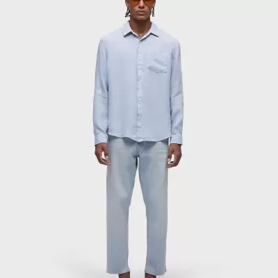 Homem com fato azul claro, sandálias castanhas e óculos de sol em fundo branco