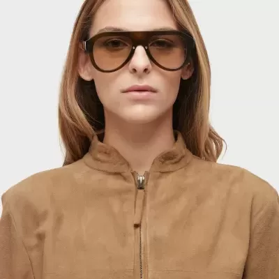 Mulher com óculos de sol castanhos e casaco castanho claro