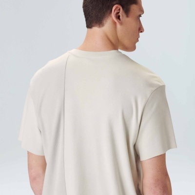 T-shirt bege claro de costas com costura vertical ligeiramente deslocada