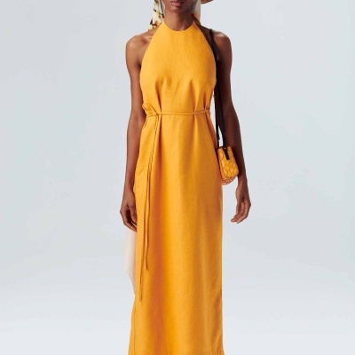 Vestido amarelo comprido com cinto, chapéu de palha, mini bolsa e sandálias.