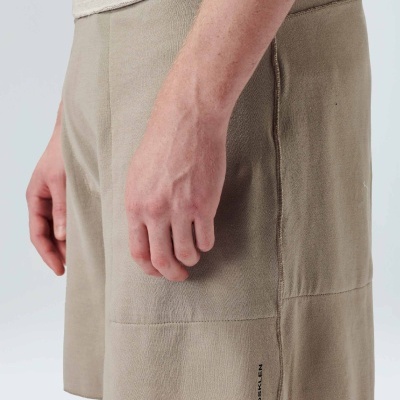 Calções bege com bolso lateral e logótipo preto usado por uma pessoa