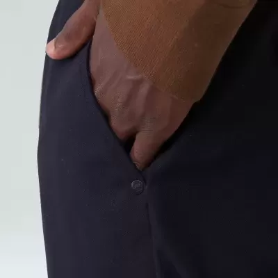 Mão com manga castanha no bolso de calças pretas com botão