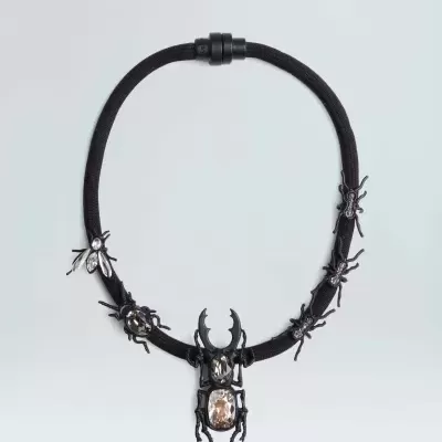 Colar preto com figuras de insetos e besouro central com pedra brilhante