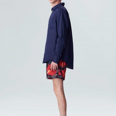 Homem vestido casual com camisa azul, calções camuflados e sapatos vermelhos