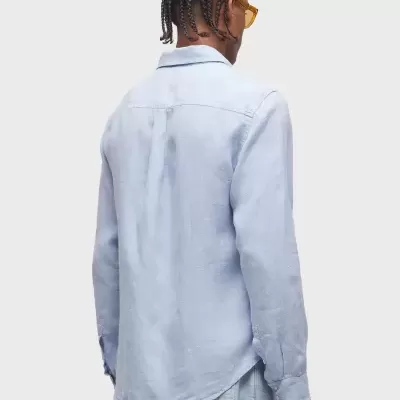 Homem visto de costas usando camisa azul clara de manga comprida e calças jeans azul claro