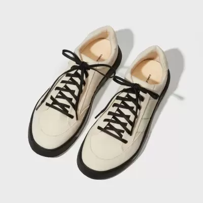 Sapatilhas brancas com sola preta e atacadores pretos