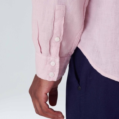 Manga de camisa rosa clara com botões brancos e parte de calça azul escura