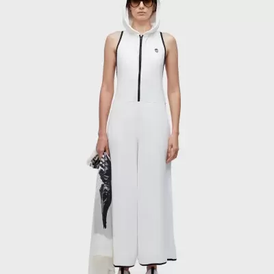 Macacão branco com capuz e fecho preto, usado por mulher com óculos escuros e ténis brancos