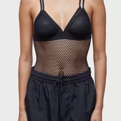 Top feminino preto de malha com padrão de rede e calças pretas largas.