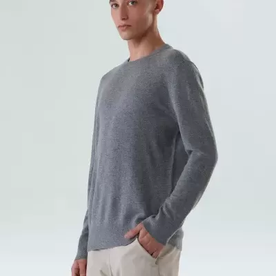 Homem com camisola cinza e calças bege em fundo claro