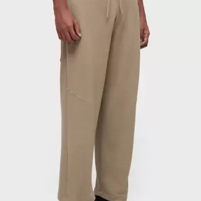 Calças amplas de malha bege com cordão na cintura e sapatilhas negras e brancas