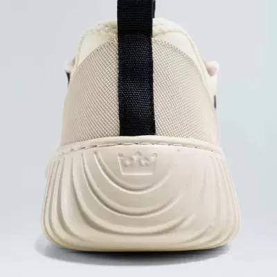 Ténis bege com sola branca e faixa preta no calcanhar visto por trás