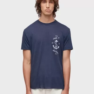 Homem a usar t-shirt azul escura com estampa branca e calças bege claras