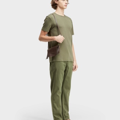 Homem com roupa verde e sandálias castanhas em fundo branco