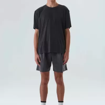 Homem com roupa desportiva preta e cinzenta, em fundo branco