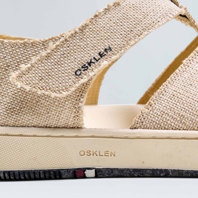 Sandália bege OSKLEN com tecido de ráfia, sola bege com detalhes coloridos e logótipos visíveis.