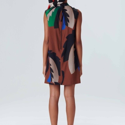 Criança com vestido colorido e chapéu de padrão geométrico vista de costas