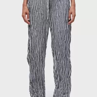 Calças compridas de riscas verticais pretas e brancas com cordão branco na cintura, usadas com sandálias pretas e sola clara