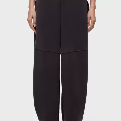 Calças pretas largas com costura e ténis brancos.