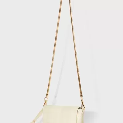 Mala pequena creme com alça dourada em fundo branco