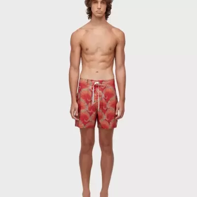 Calções de banho vermelhos com padrões azuis e cordão branco modelados por homem.