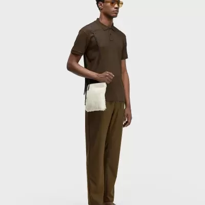 Homem com roupa castanha, óculos amarelos e bolsa branca de alça preta