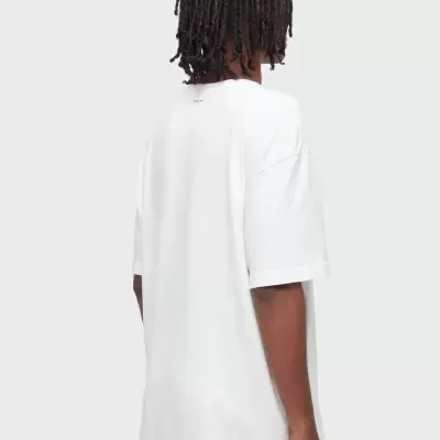 Pessoa de costas com t-shirt branca e cabelo com dreadlocks.