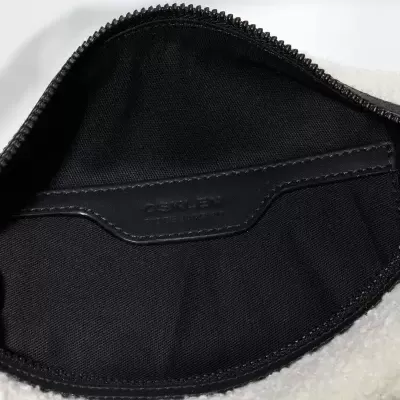 Interior de bolsa preta com fecho e etiqueta COACH em tecido branco pelúcia