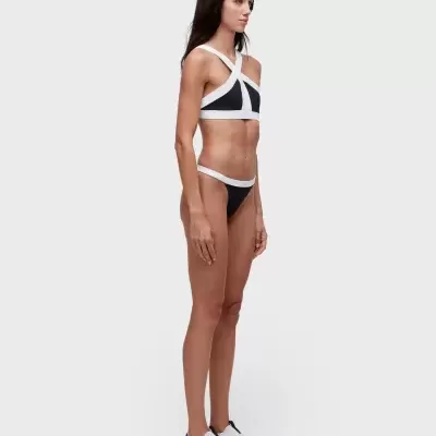 Fato de banho preto com alças brancas cruzadas e sapatos desportivos brancos.