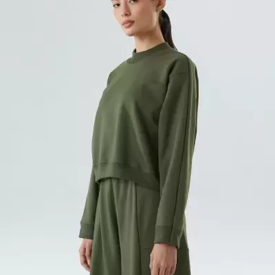 Conjunto de sweatshirt e calças largas verdes em fundo neutro claro