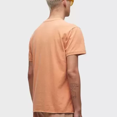 Homem de costas com t-shirt e calções laranja em fundo cinza claro