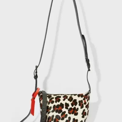 Mala de tiracolo com padrão animal e etiquetas penduradas