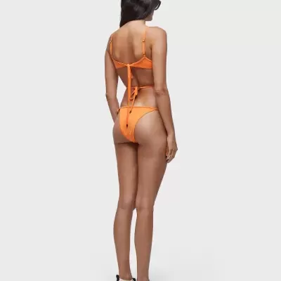 Mulher a usar bikini laranja vista de costas em fundo cinza