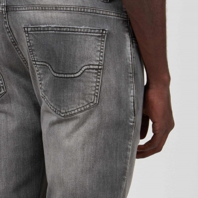 Parte traseira de calças de ganga cinza com bolso traseiro e costura decorativa, usada por pessoa.